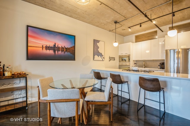 dining area with dark hardwood / wood-style floors and rail lighting