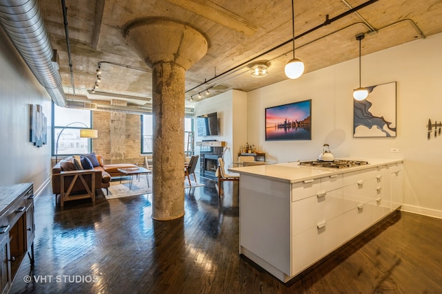 kitchen with decorative light fixtures, dark hardwood / wood-style floors, stainless steel gas cooktop, white cabinetry, and ornate columns