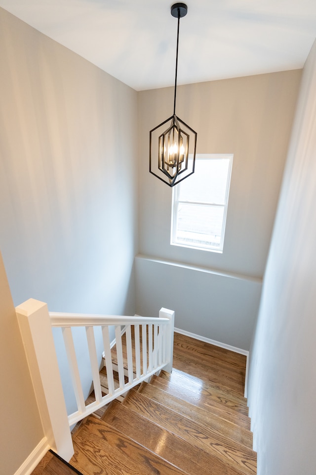 stairs with hardwood / wood-style floors and a chandelier