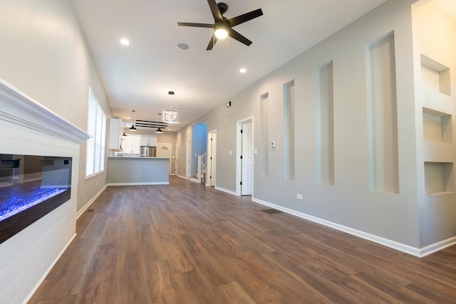 unfurnished living room featuring dark hardwood / wood-style floors and ceiling fan