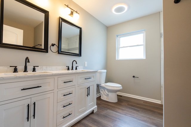 bathroom featuring dual sinks, oversized vanity, toilet, and wood-type flooring