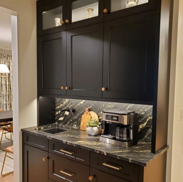 bar with sink, dark stone counters, and tasteful backsplash