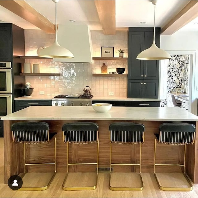 kitchen featuring pendant lighting, light hardwood / wood-style floors, a kitchen bar, and tasteful backsplash