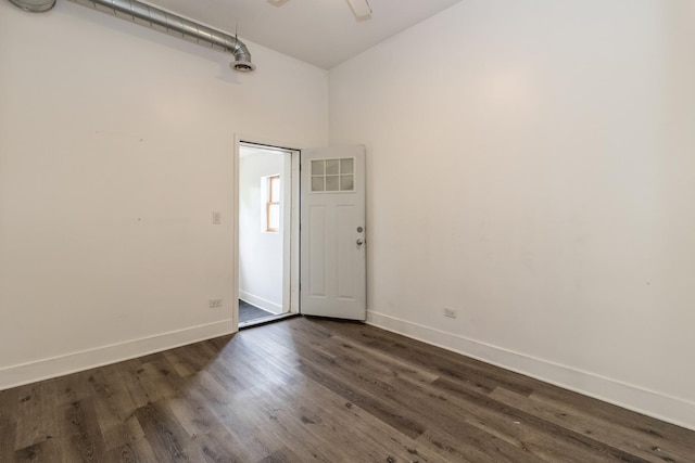 spare room with a high ceiling and dark wood-type flooring