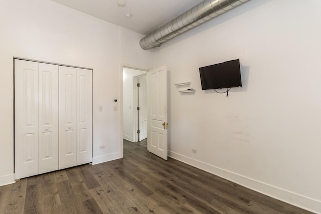 unfurnished bedroom with dark hardwood / wood-style flooring and a closet