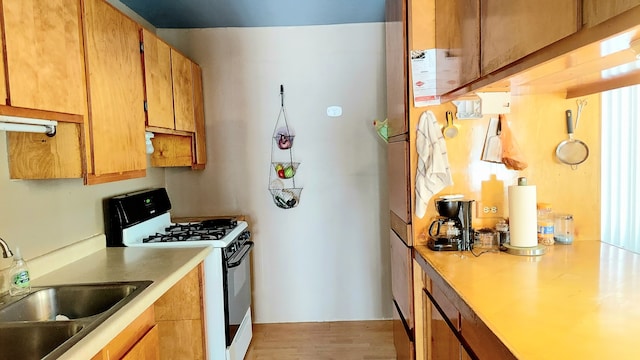 kitchen featuring white gas range, sink, and light wood-type flooring