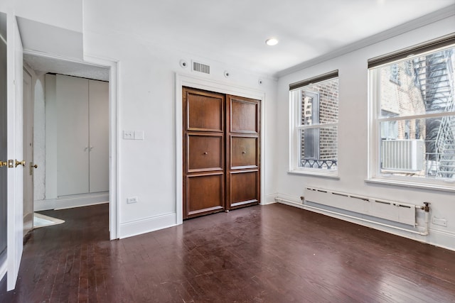 unfurnished bedroom with a baseboard radiator and dark hardwood / wood-style floors