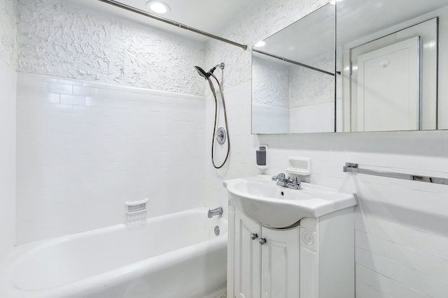 bathroom with tile walls, vanity, and tiled shower / bath combo