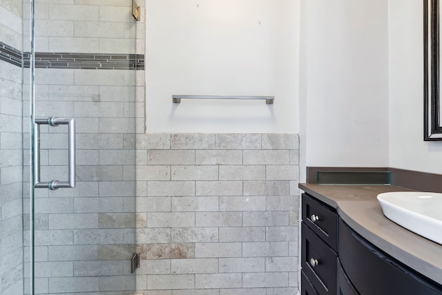 bathroom featuring a shower with door and vanity