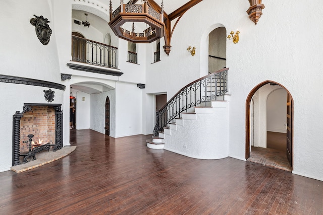 interior space with a high ceiling, a multi sided fireplace, and dark hardwood / wood-style floors