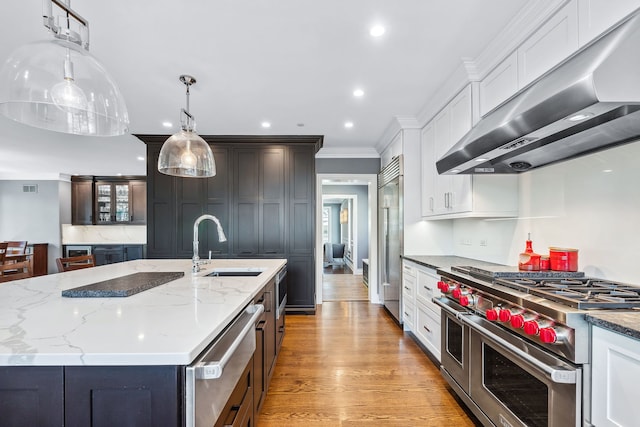 kitchen featuring light hardwood / wood-style floors, white cabinets, premium appliances, and wall chimney exhaust hood