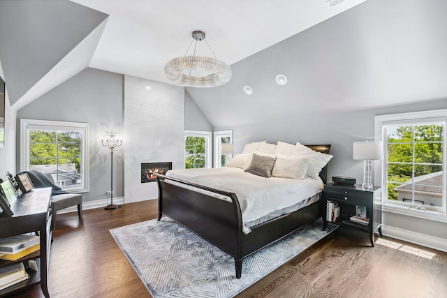 bedroom with high vaulted ceiling, dark wood-type flooring, and a large fireplace