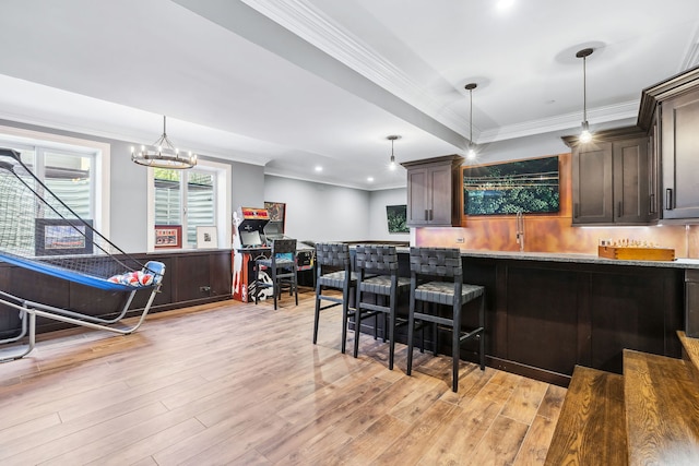 kitchen with dark brown cabinets, light stone countertops, light hardwood / wood-style floors, crown molding, and decorative light fixtures