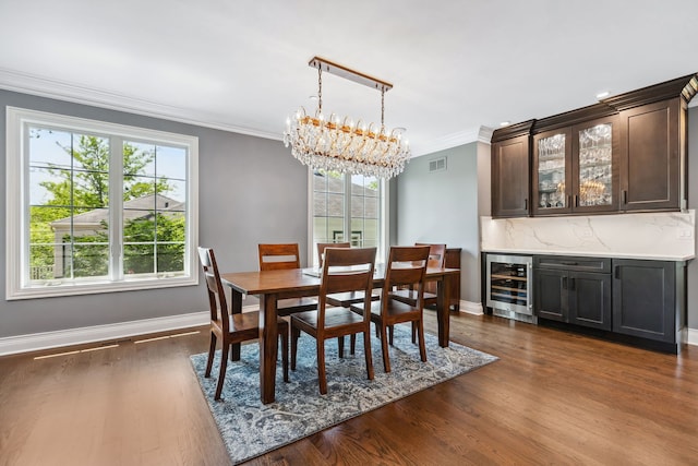 dining room featuring crown molding, dark hardwood / wood-style floors, wine cooler, and an inviting chandelier