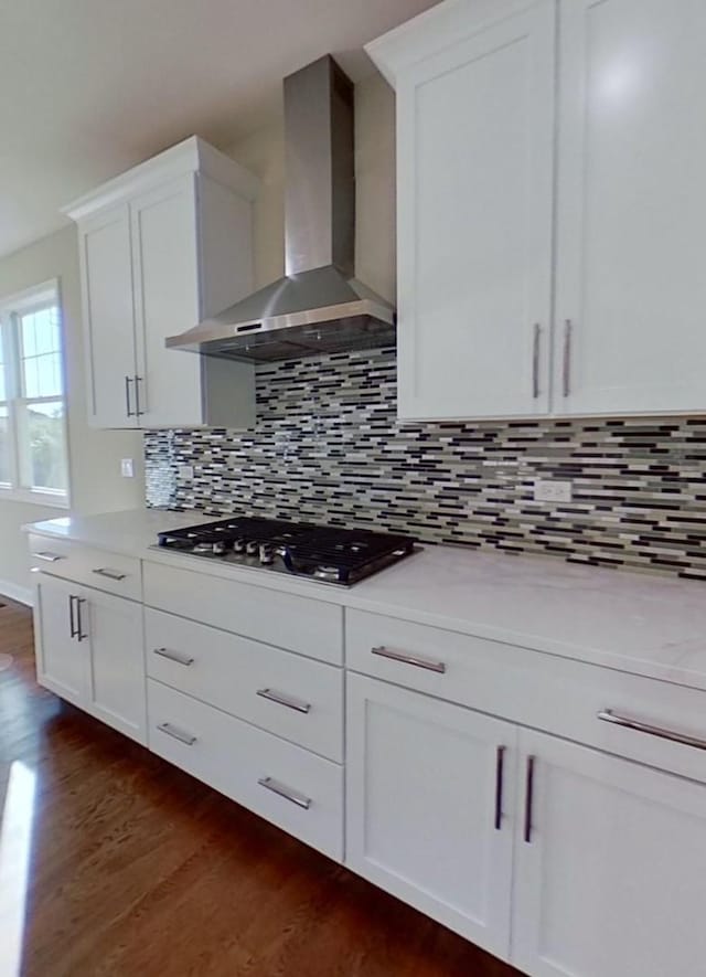 kitchen featuring dark hardwood / wood-style flooring, white cabinetry, stainless steel gas stovetop, and wall chimney range hood