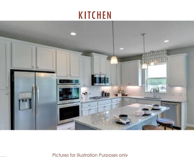 kitchen with stainless steel appliances, sink, pendant lighting, a center island, and white cabinetry