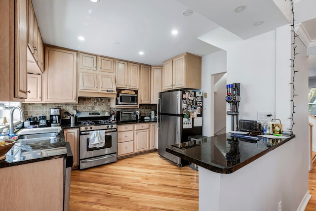 kitchen with light hardwood / wood-style floors, appliances with stainless steel finishes, kitchen peninsula, sink, and tasteful backsplash