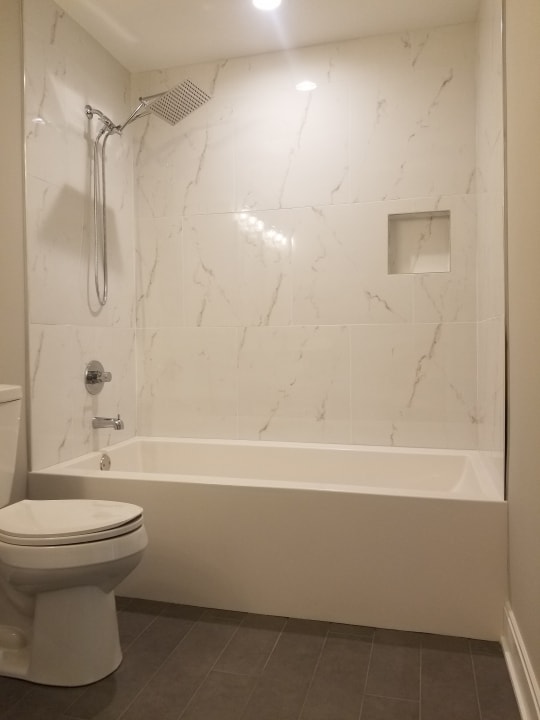 bathroom with tile flooring, toilet, and tiled shower / bath