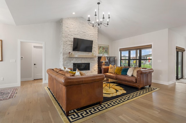 living room with high vaulted ceiling, a notable chandelier, light hardwood / wood-style flooring, and a fireplace