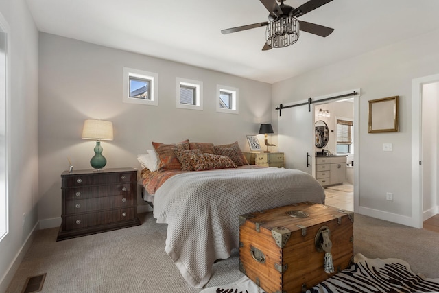 carpeted bedroom with a barn door, ensuite bathroom, and ceiling fan