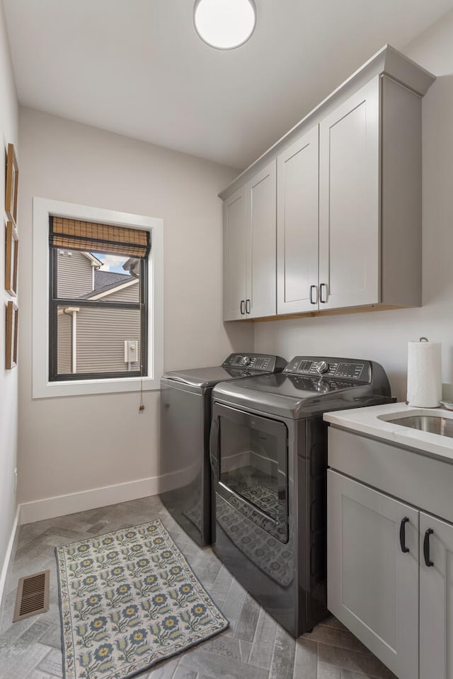 clothes washing area with cabinets, sink, and washing machine and clothes dryer