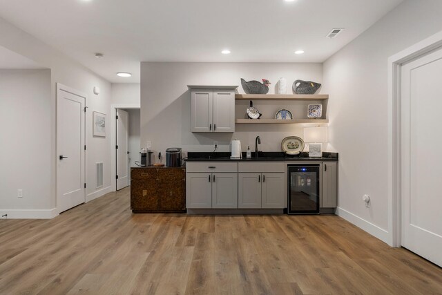 kitchen with wine cooler, gray cabinets, light hardwood / wood-style flooring, and sink