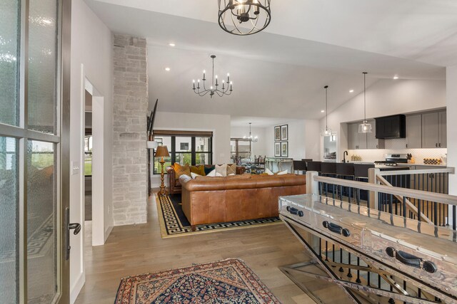 interior space featuring high vaulted ceiling, light hardwood / wood-style floors, and a chandelier