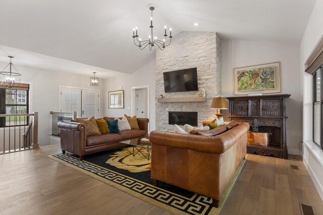 living room with a notable chandelier, hardwood / wood-style floors, high vaulted ceiling, and a fireplace