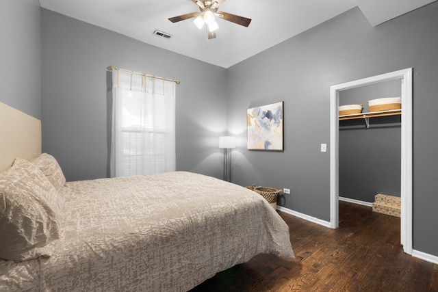 bedroom with a spacious closet, dark wood-type flooring, a closet, and ceiling fan