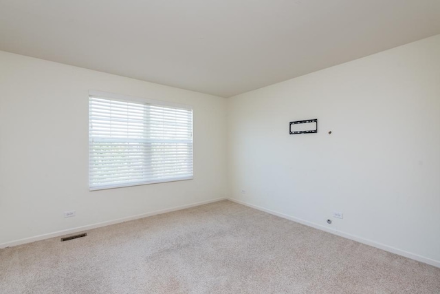 spare room featuring light carpet, baseboards, and visible vents