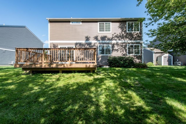 back of house with a storage shed, an outdoor structure, a lawn, and a wooden deck