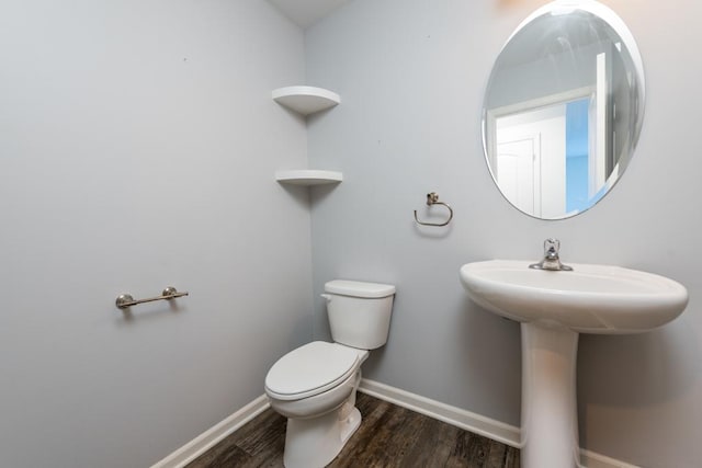 half bath featuring baseboards, toilet, and wood finished floors