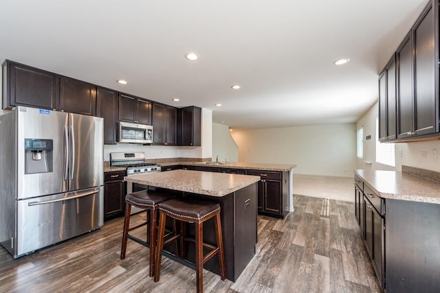 kitchen with stainless steel appliances, a sink, light countertops, a center island, and a kitchen bar