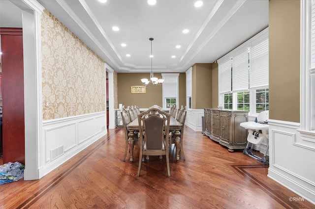 dining area with an inviting chandelier, hardwood / wood-style floors, and a tray ceiling