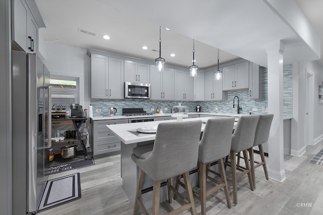 kitchen featuring a center island, light hardwood / wood-style flooring, stainless steel appliances, a breakfast bar area, and tasteful backsplash