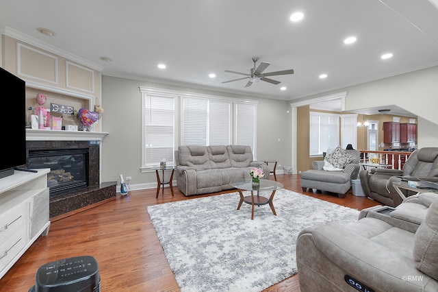 living room with crown molding, hardwood / wood-style flooring, ceiling fan, and a high end fireplace