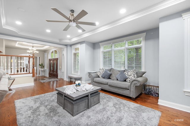 living room featuring hardwood / wood-style floors, a tray ceiling, crown molding, and ceiling fan with notable chandelier