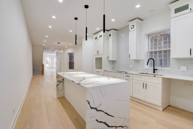 kitchen with backsplash, white cabinets, sink, and light hardwood / wood-style flooring