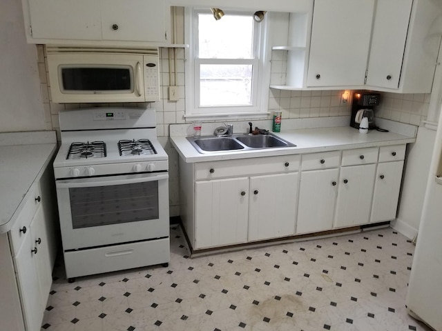 kitchen with backsplash, white cabinetry, white appliances, and sink