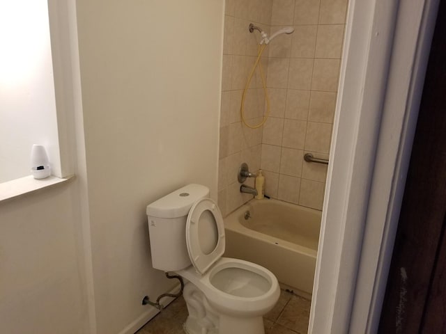 bathroom with tile patterned flooring, tiled shower / bath, and toilet