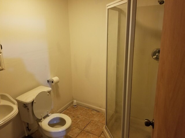 bathroom with a shower with door and toilet