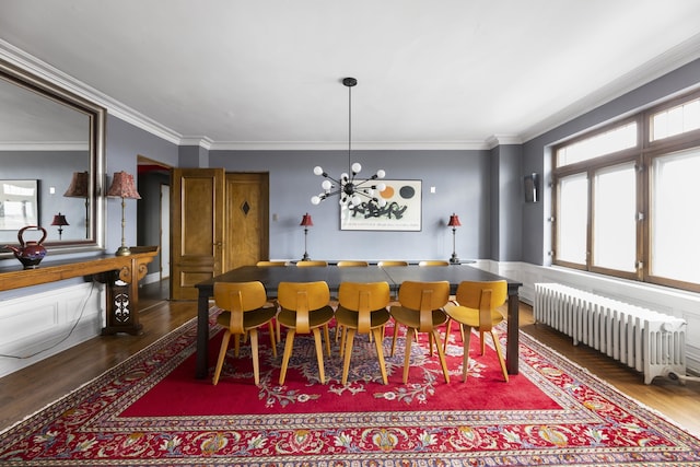 dining space with crown molding, dark hardwood / wood-style floors, radiator, and a notable chandelier