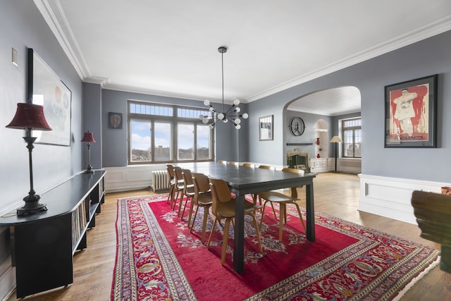 dining room with ornamental molding, radiator heating unit, a chandelier, and wood-type flooring