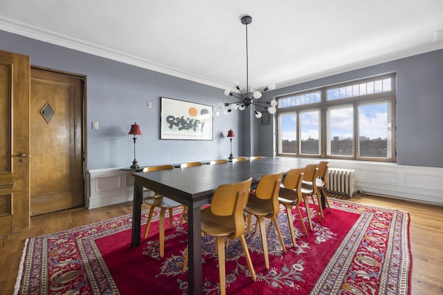 dining space featuring a notable chandelier, hardwood / wood-style flooring, radiator, and crown molding