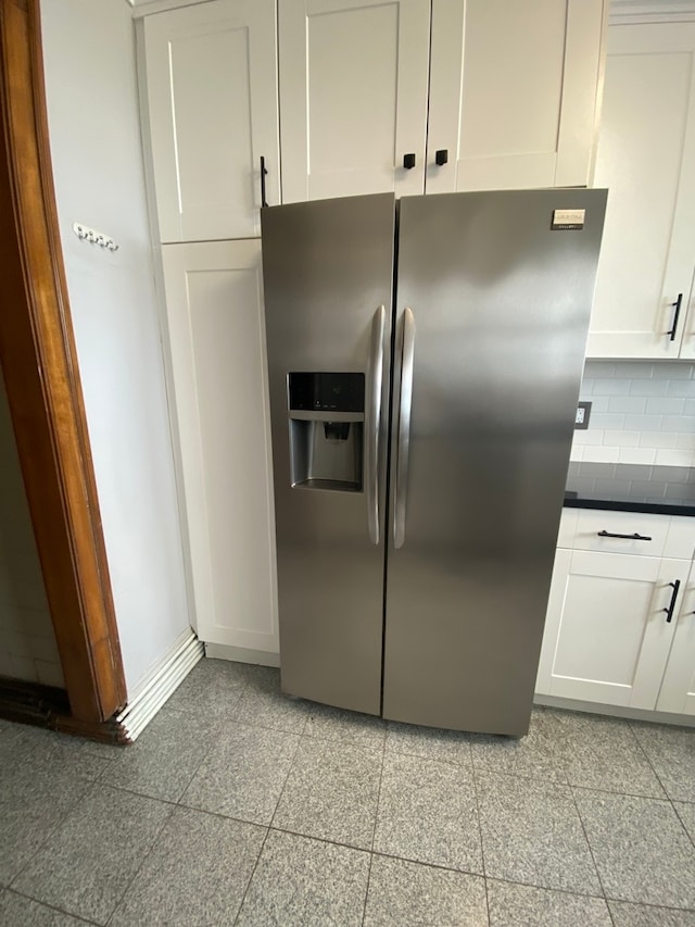 kitchen with white cabinetry, stainless steel fridge with ice dispenser, backsplash, and light tile flooring