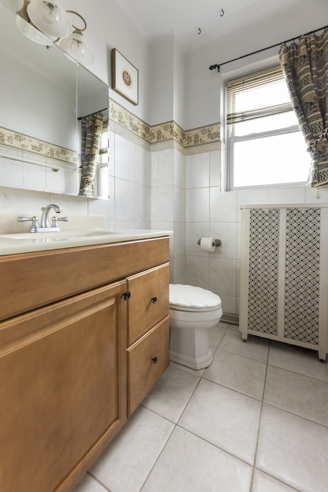 bathroom with tile walls, toilet, tile floors, radiator heating unit, and vanity