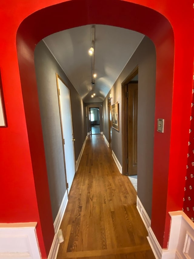 hallway with wood-type flooring and vaulted ceiling