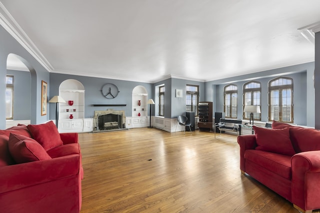 living room with crown molding, a healthy amount of sunlight, hardwood / wood-style floors, and built in shelves