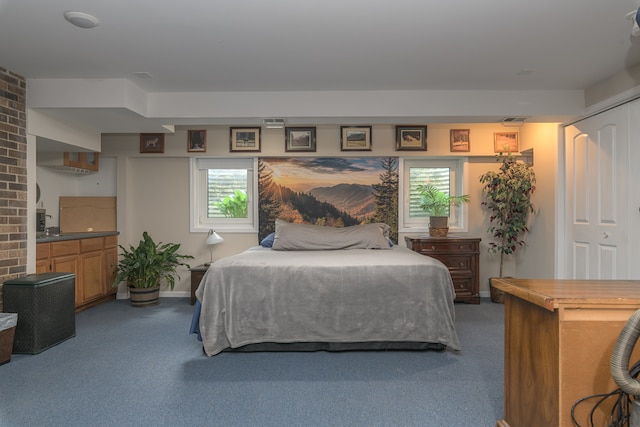 bedroom with a closet, carpet floors, and brick wall