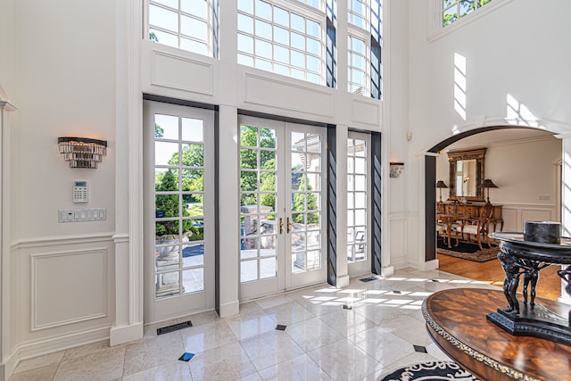 entryway with a towering ceiling, french doors, and light hardwood / wood-style flooring